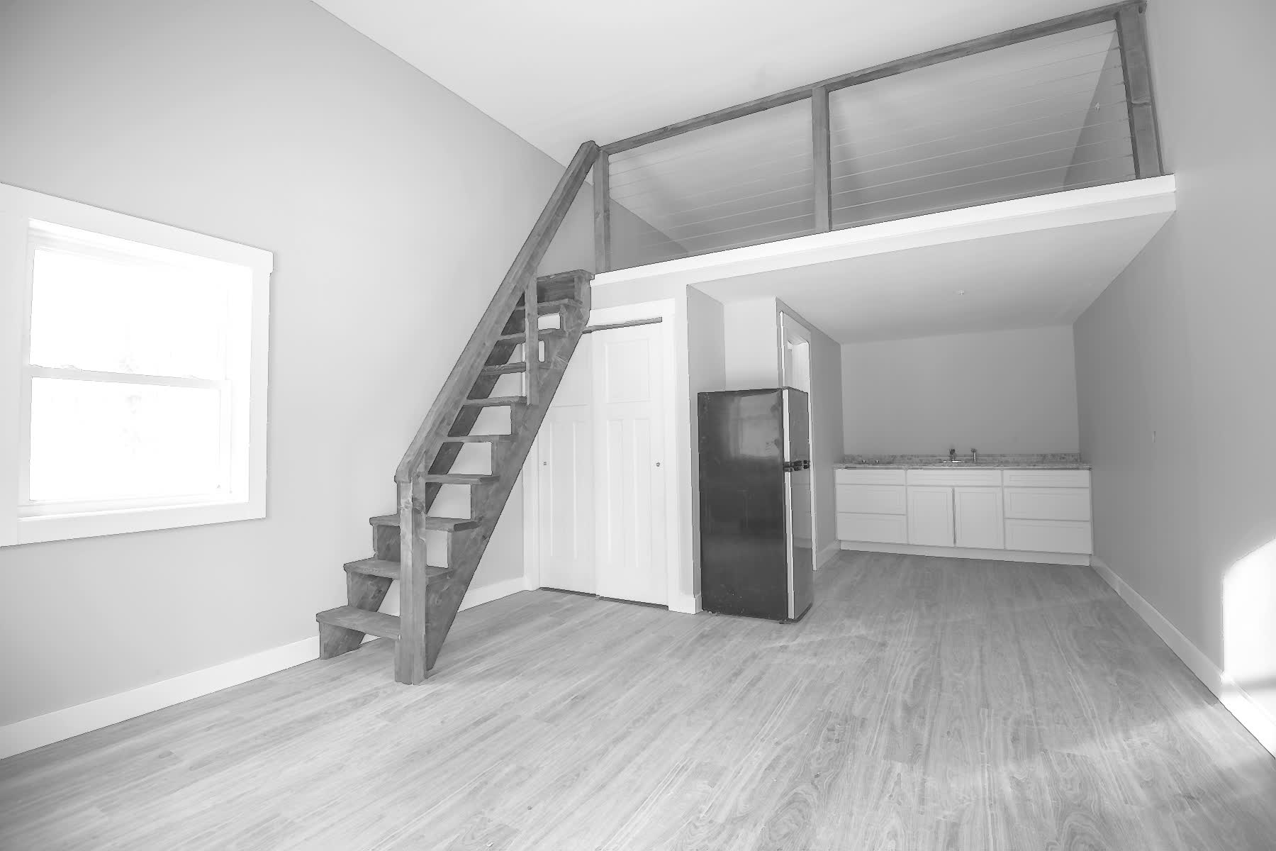 Finished studio apartment with loft stair and kitchenette after redevelopment